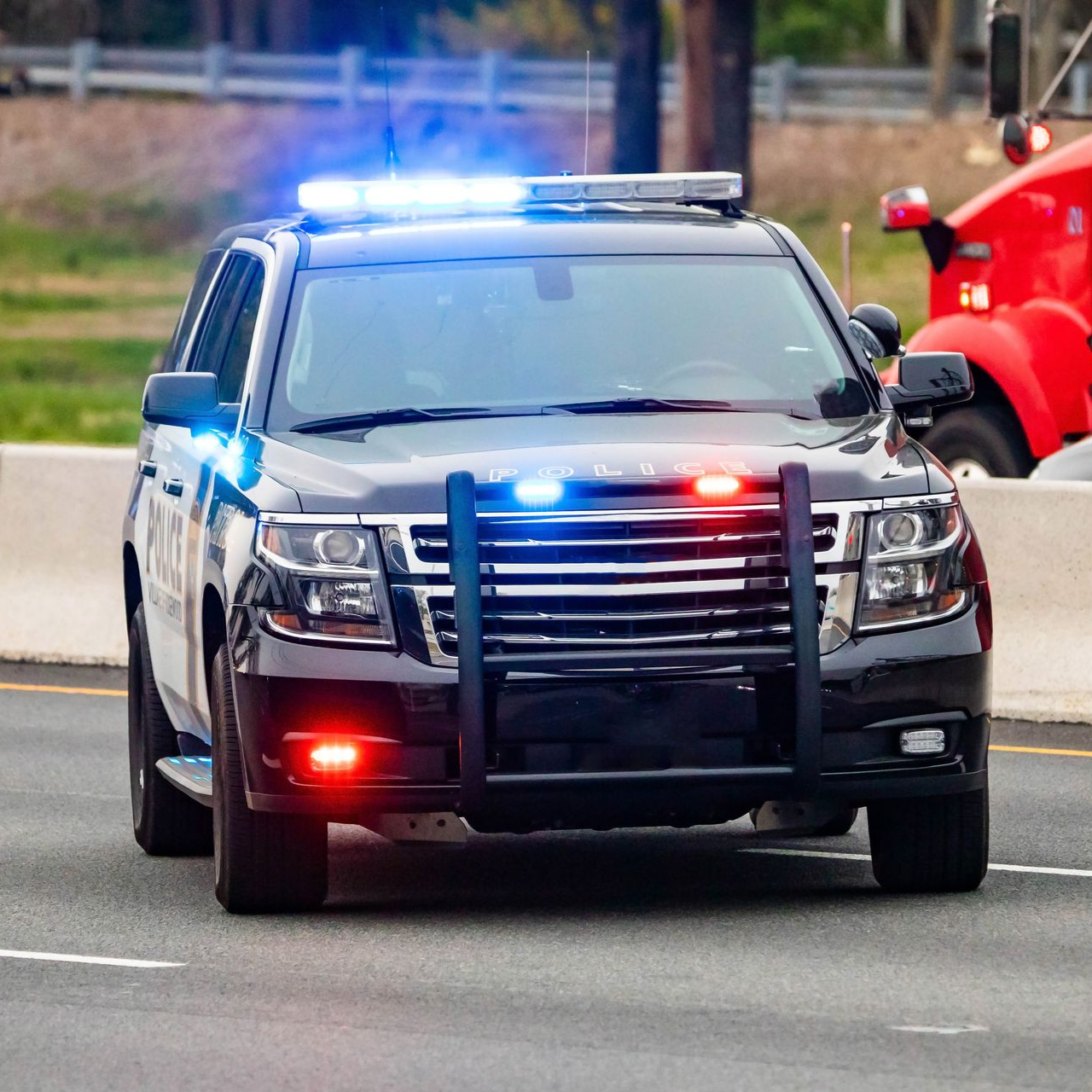 Black police SUV with flashing red and blue lights driving on a road