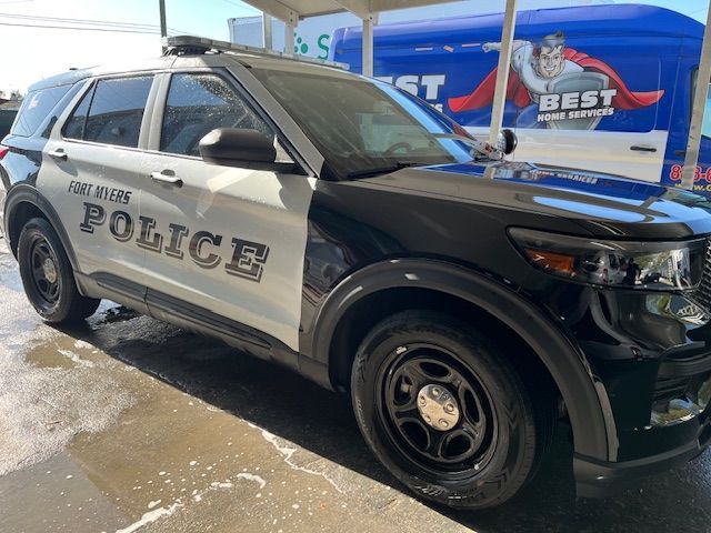 Black and white police SUV parked outside a Best Buy store in winter conditions
