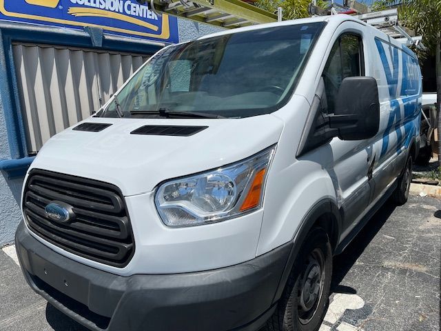 White Ford cargo van parked outdoors in front of a blue building