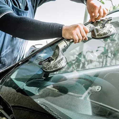 Person using suction cups to remove a car windshield.