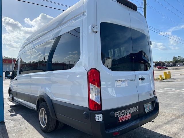 White passenger van parked outdoors under a cloudy sky, rear three-quarter view.