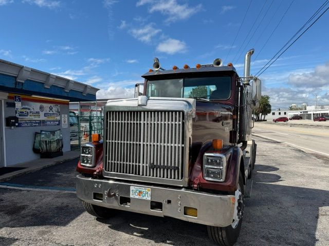 Front view of a red semi truck parked beside a gas station on a sunny day