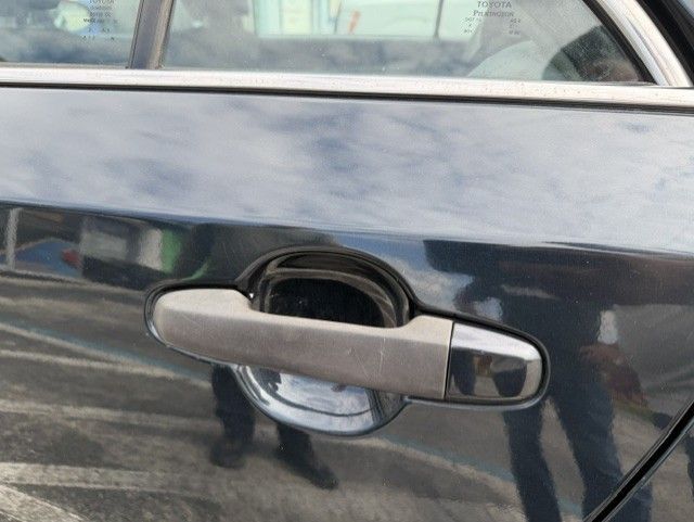 Close-up of a gray car door handle on a dark blue vehicle with a reflection in the paint