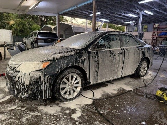 Car covered in thick foam at a car wash under a covered bay
