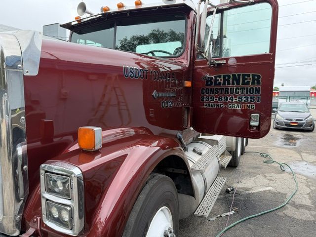 Maroon semi truck with open door parked at a construction site