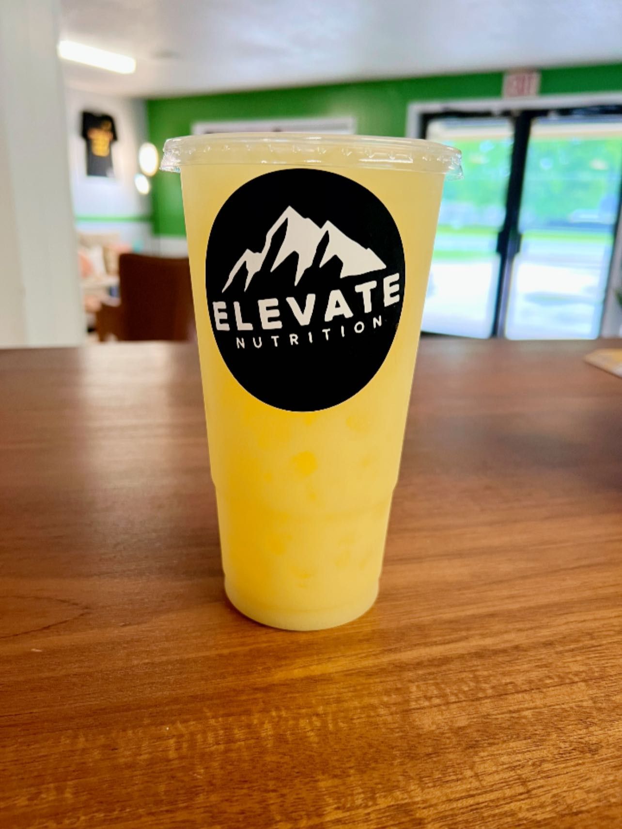 A plastic cup of yellow iced tea or juice with an 