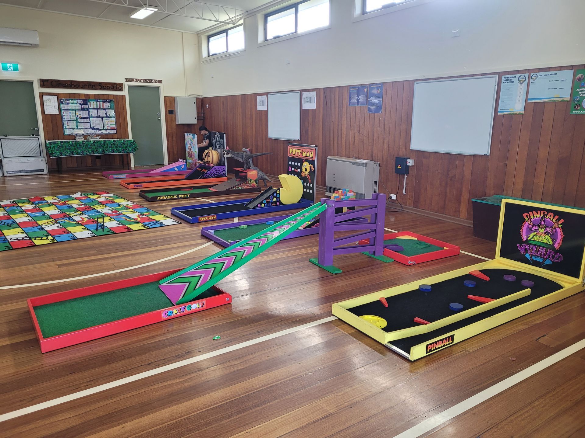 Indoor mini golf course setup on a wooden floor with multiple colorful obstacles.