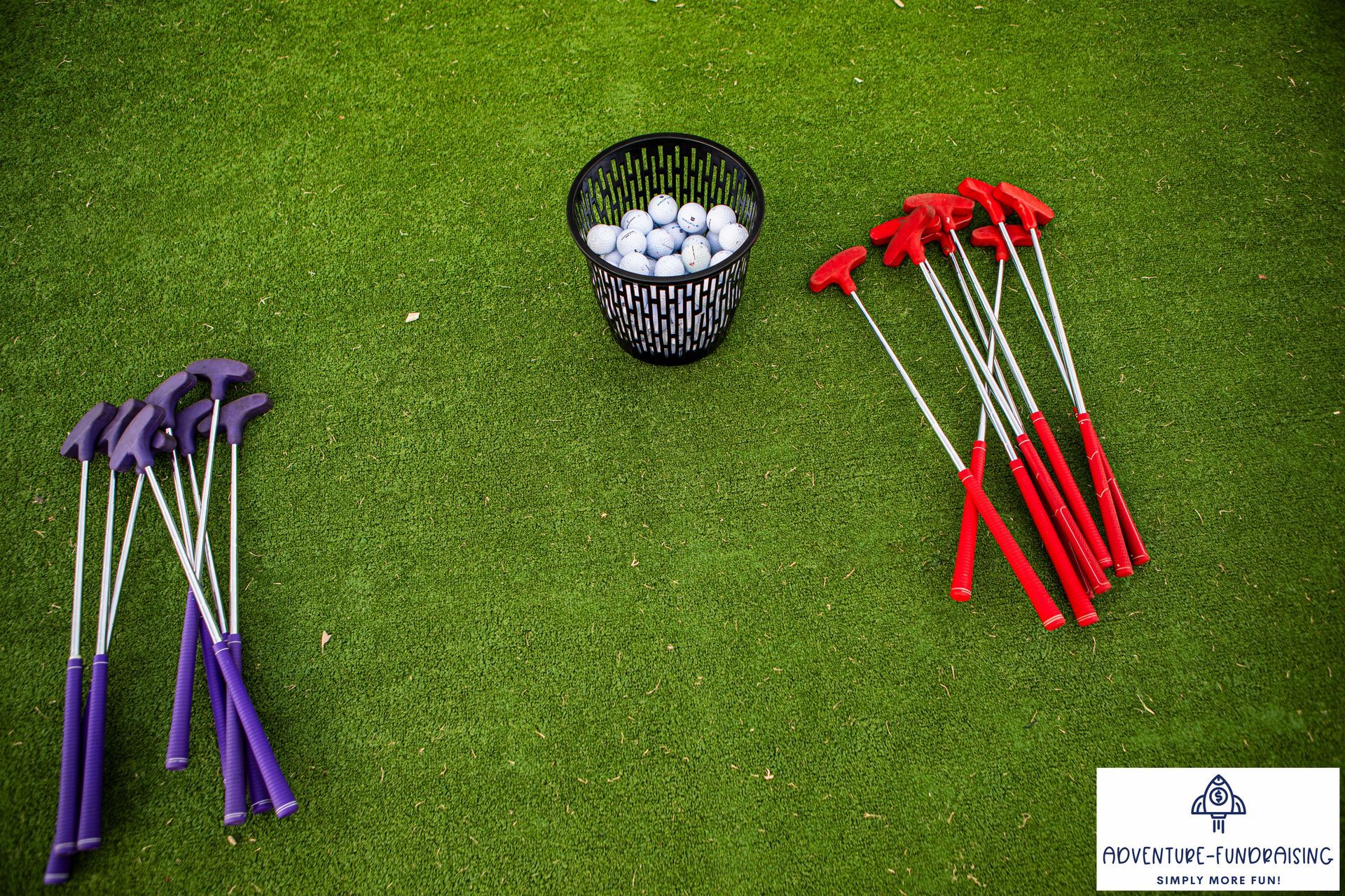 Miniature golf putters and golf balls on green turf.