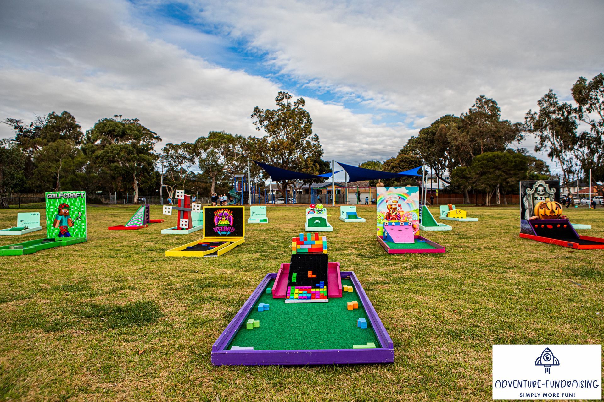 Miniature golf course set up on grassy field, various colorful obstacles and designs.