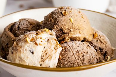 Assorted scoops of ice cream in a bowl, including chocolate, vanilla, and caramel flavors.