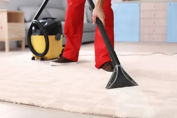 A person is using a vacuum cleaner to clean a carpet in a living room.