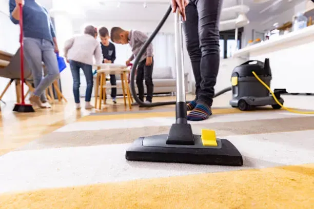 A person is using a vacuum cleaner to clean a carpet in a living room.