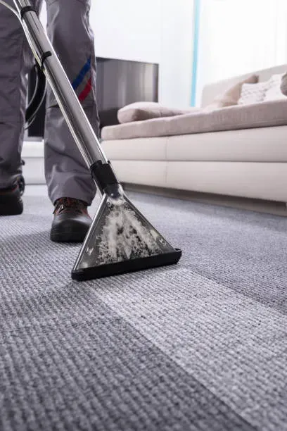 A person is using a vacuum cleaner to clean a carpet in a living room.