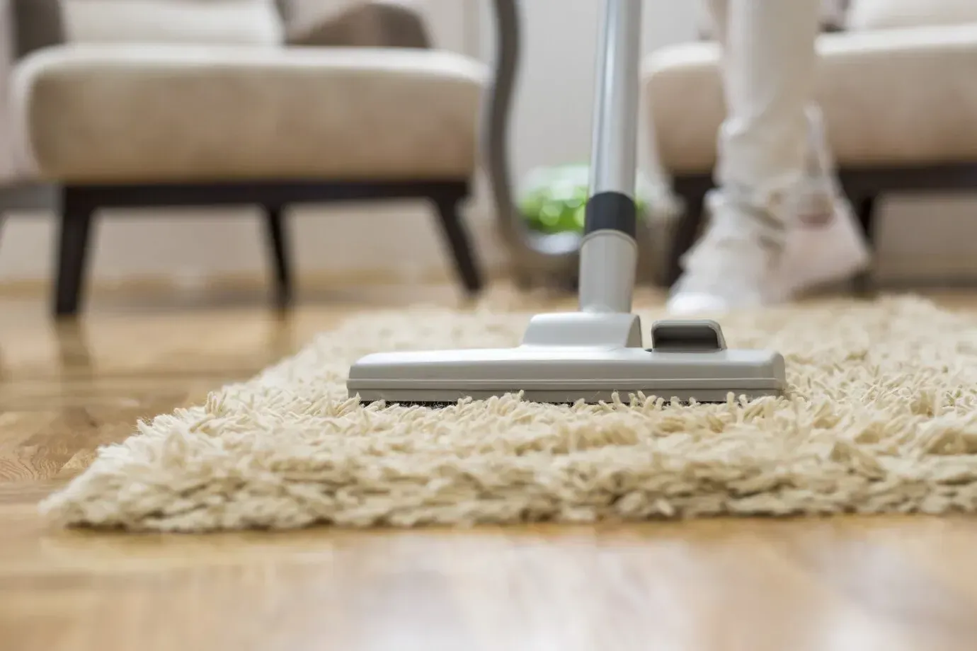 A person is vacuuming a rug in a living room.