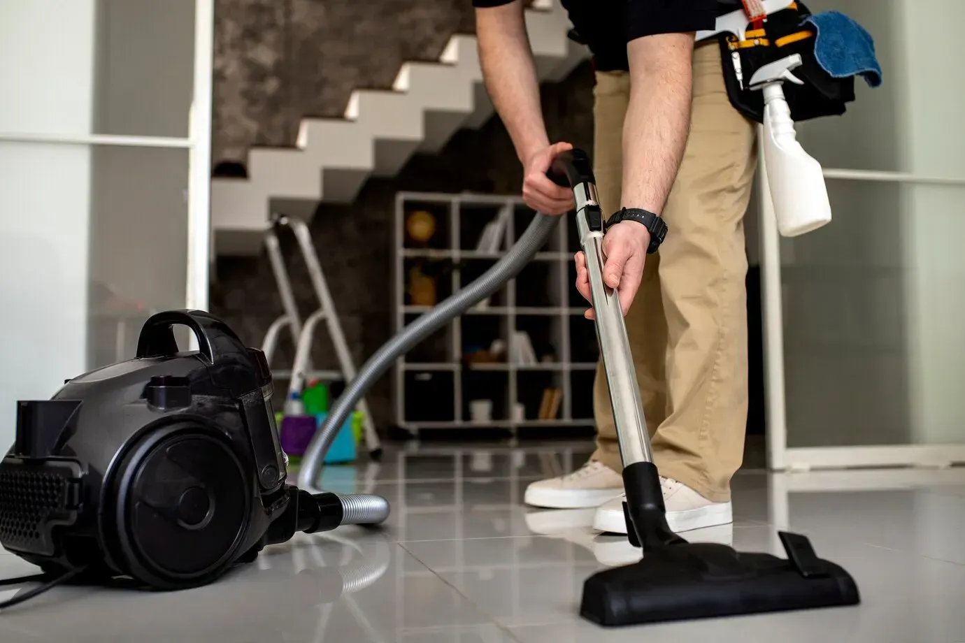 A man is cleaning the floor with a vacuum cleaner.