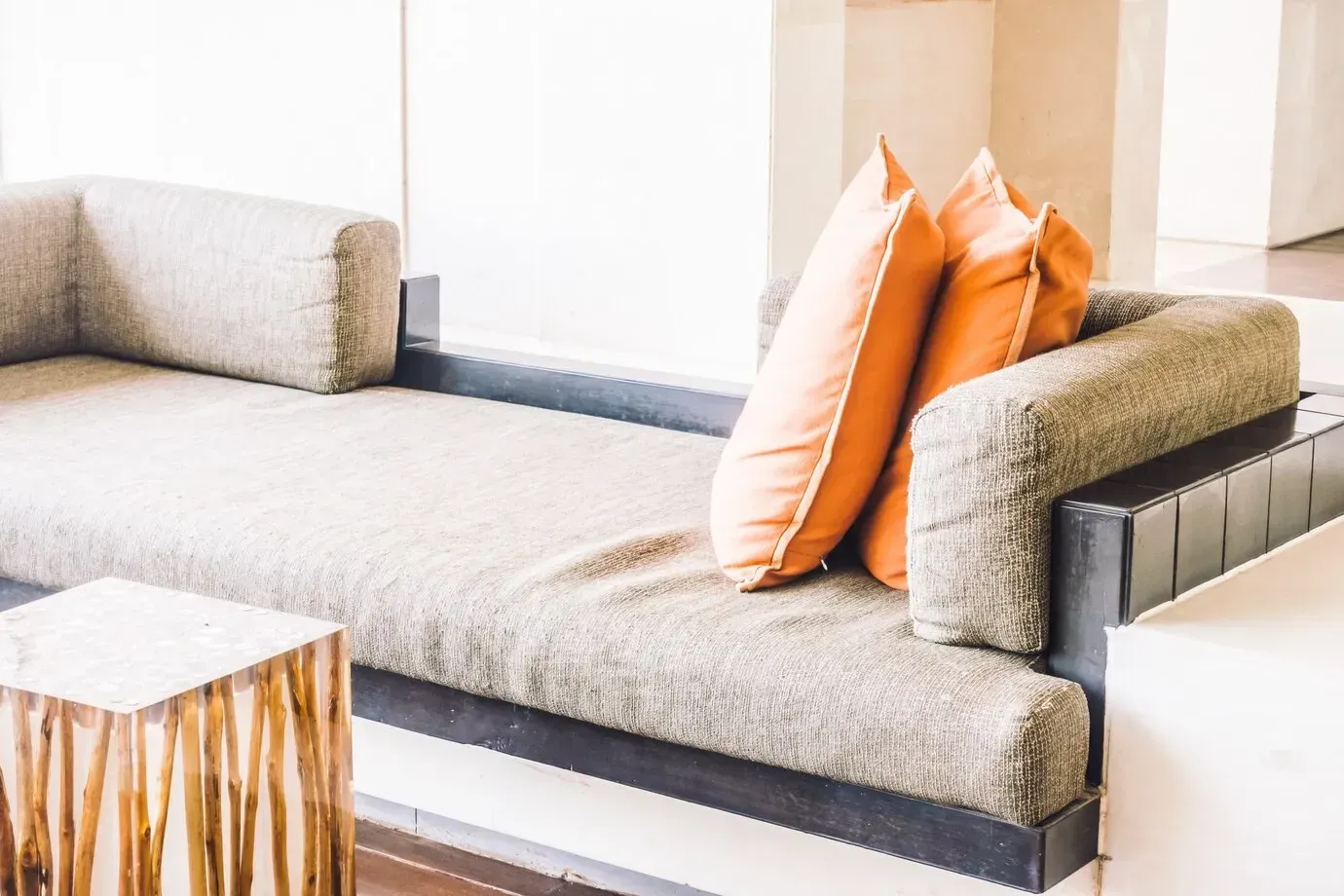 A couch with orange pillows on it in a living room.