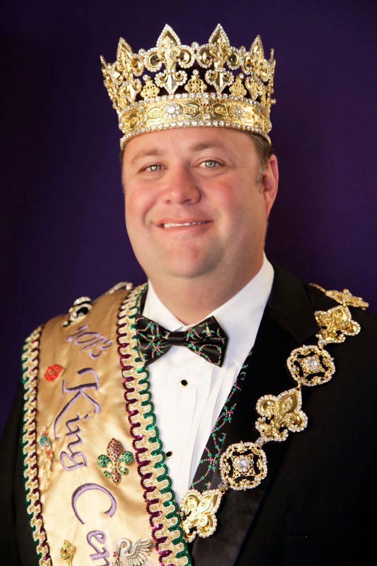 A man wearing a crown and a sash that says king
