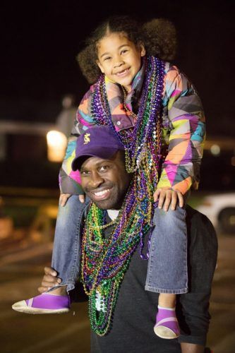 A man is carrying a little girl on his shoulders.