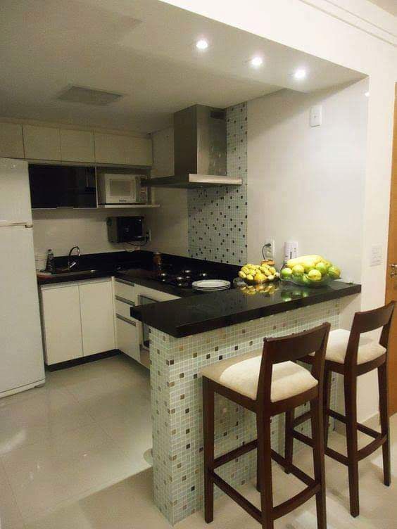 Cocina moderna con encimeras negras, isla alicatada y dos taburetes de madera.
