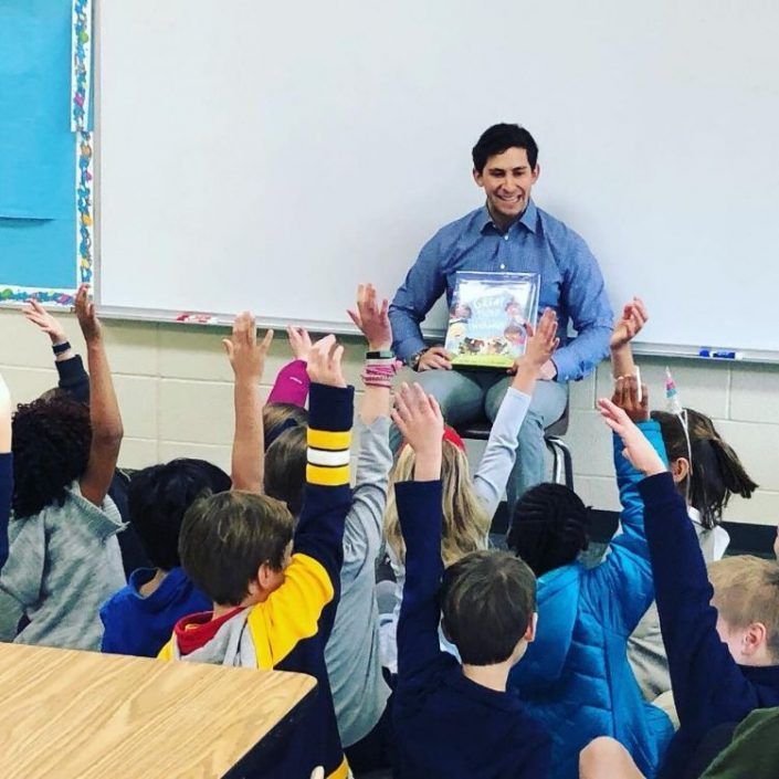 A man is reading a book to a group of children