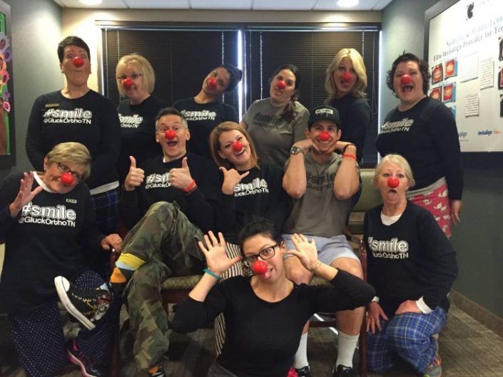 A group of people wearing red clown noses are posing for a picture