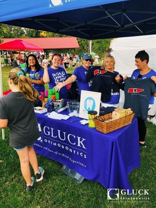 A group of people standing around a table that says gluck orthodontics