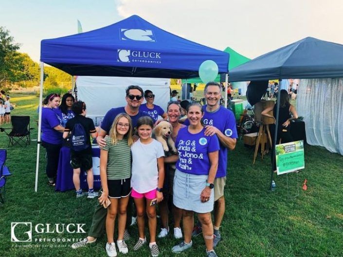 A group of people posing for a picture in front of a blue tent that says glück