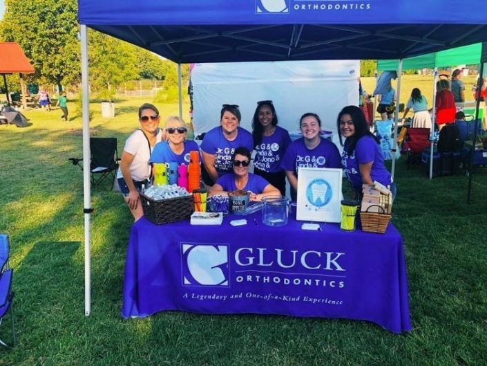 A group of people standing around a table that says gluck orthodontics