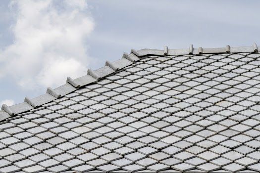 A close up of a tiled roof with a blue sky in the background.