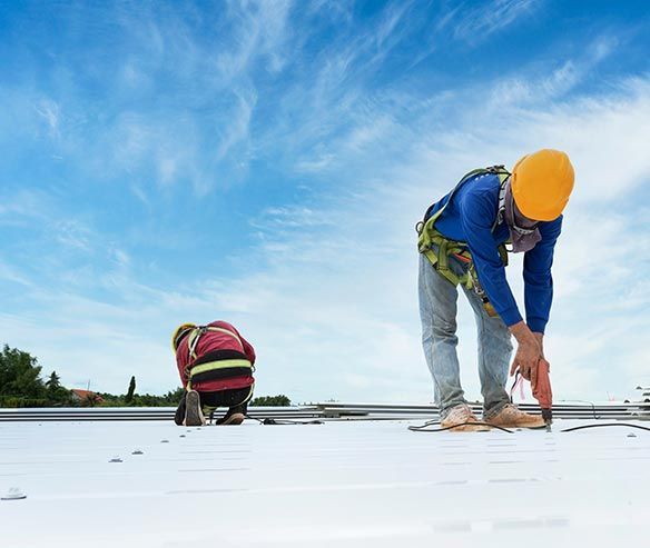 two construction workers installing or repairing a reflective white rooftop under a cloudy sky. two construction workers installing or repairing a reflective white rooftop under a cloudy sky.