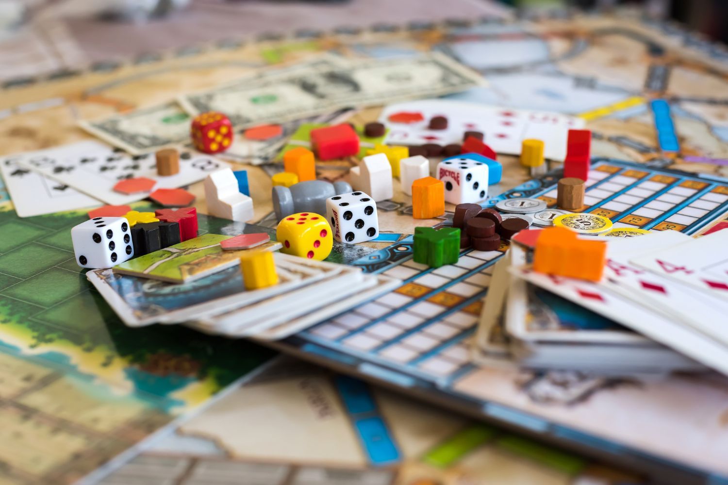 Board game in progress; dice, colorful wooden pieces, cards, and play money on the board.