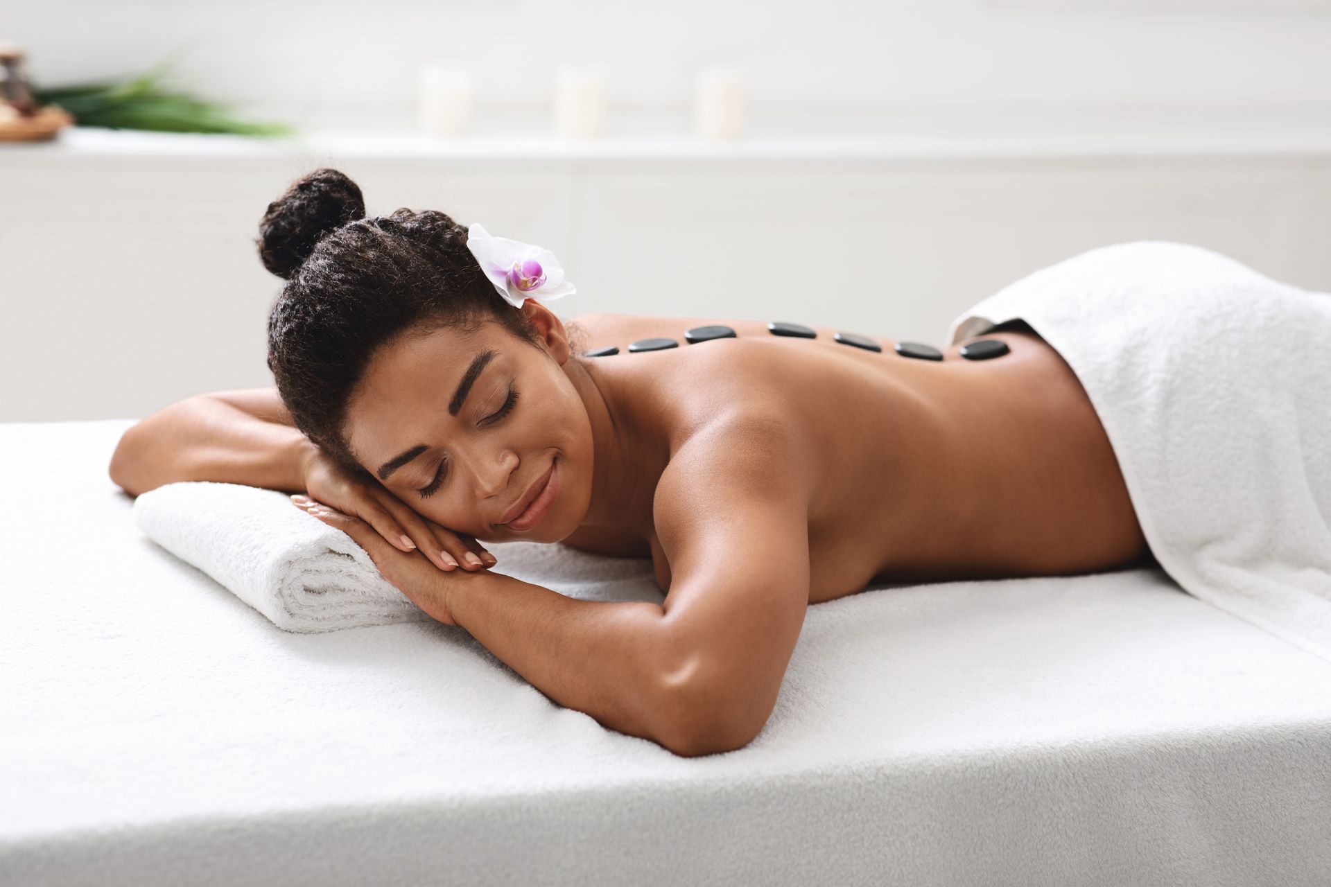 A Woman is Laying on a Massage Table With Rocks on Her Back