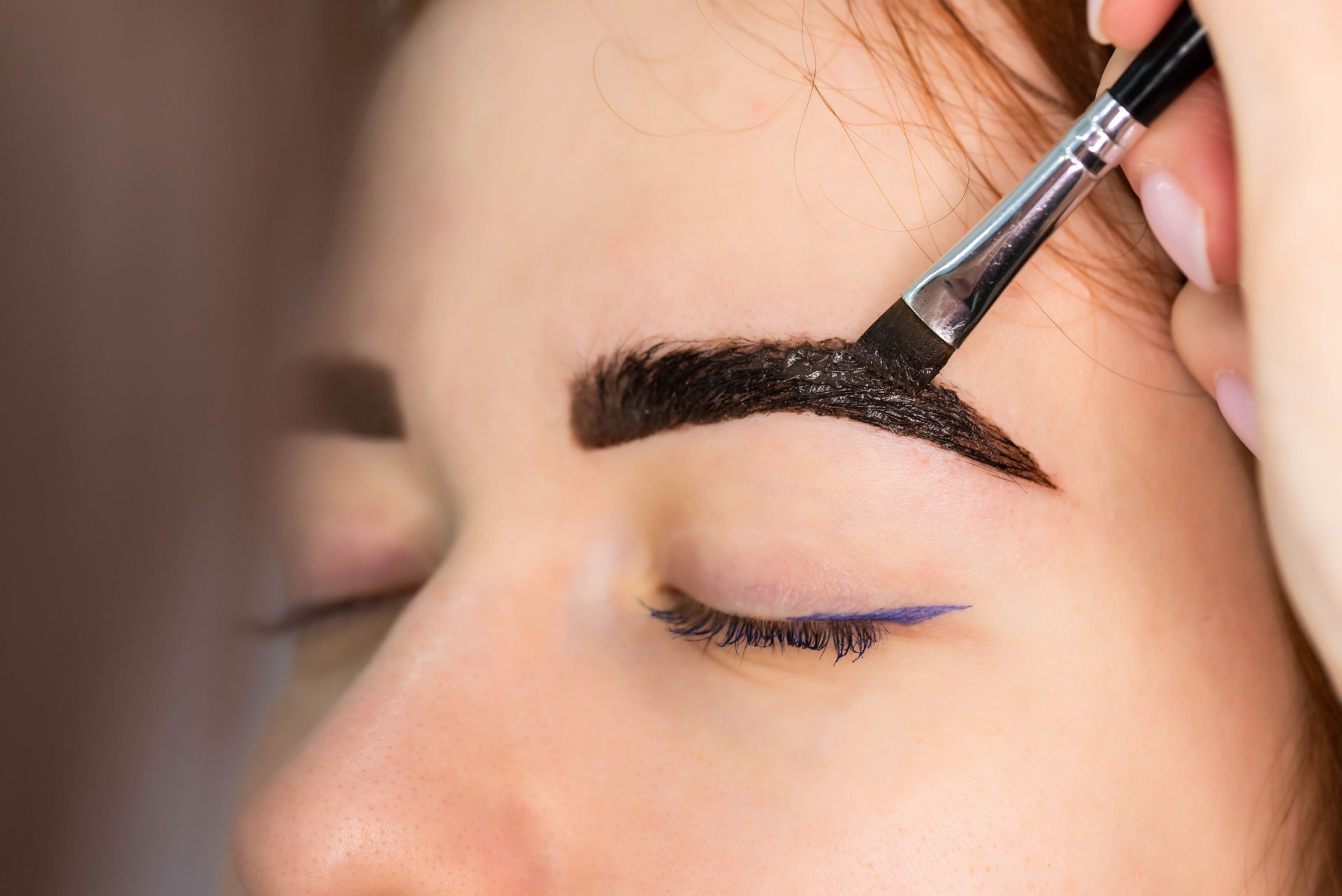 A Woman is Getting Her Eyebrows Painted With a Brush