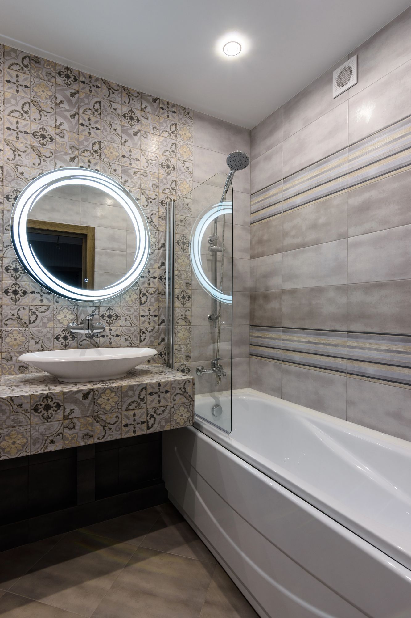 Bagno moderno con piastrelle a motivi, lavabo ovale e vasca da bagno.