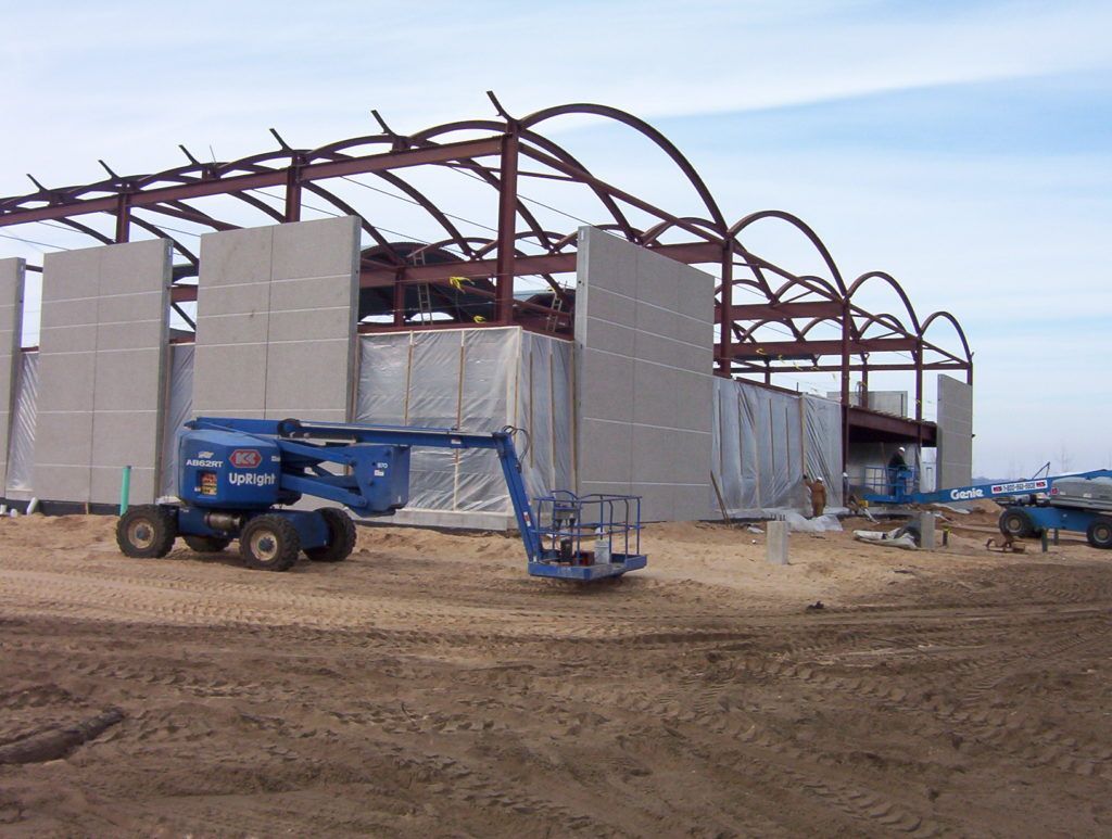 Construction site with blue boom lift beside a steel-frame building under construction