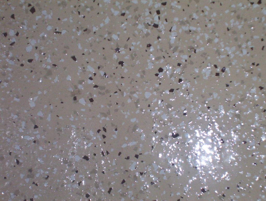 Close-up of a beige speckled terrazzo surface with a bright reflection on the right