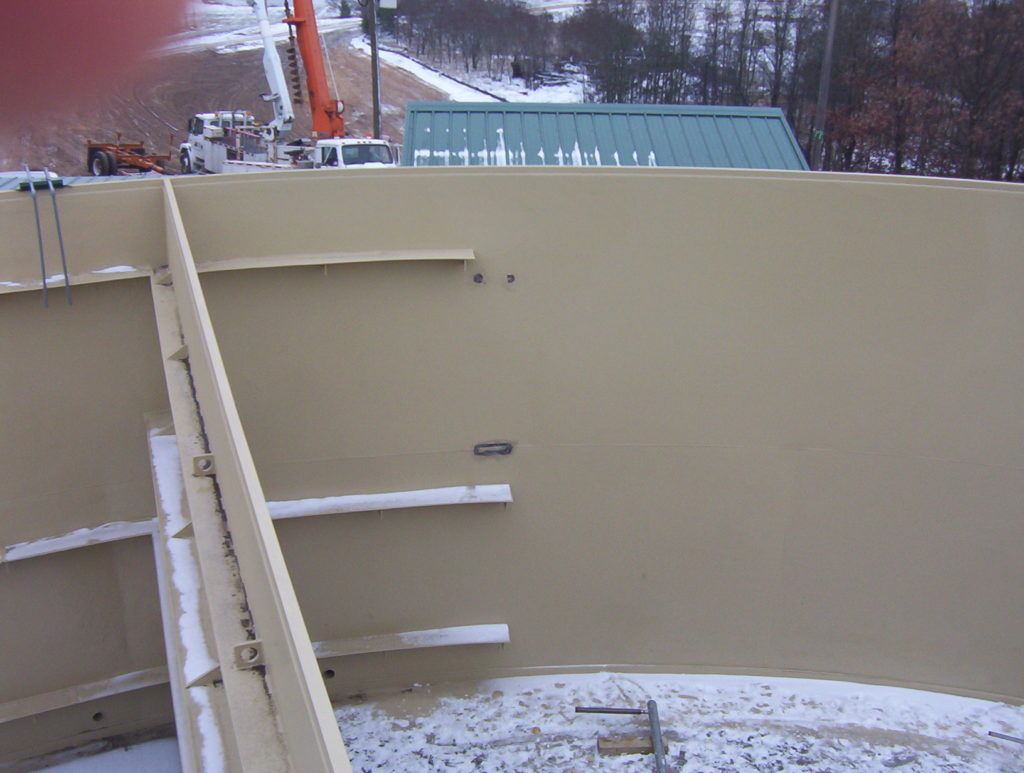 Snowy tan metal structure with stairs and railings, viewed outdoors in winter