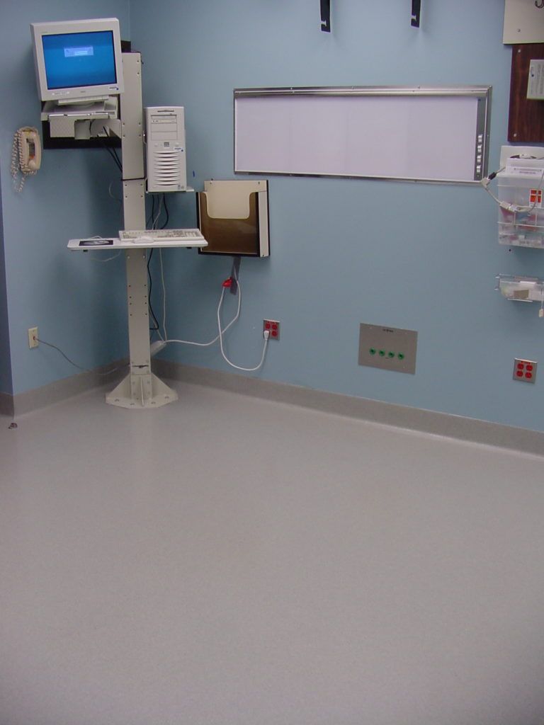 Hospital room with wall-mounted medical equipment, monitor, and outlets on a light blue wall.