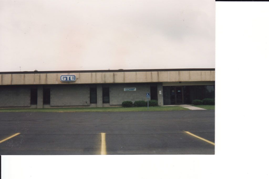 Empty strip mall storefronts with a parking lot in front under an overcast sky