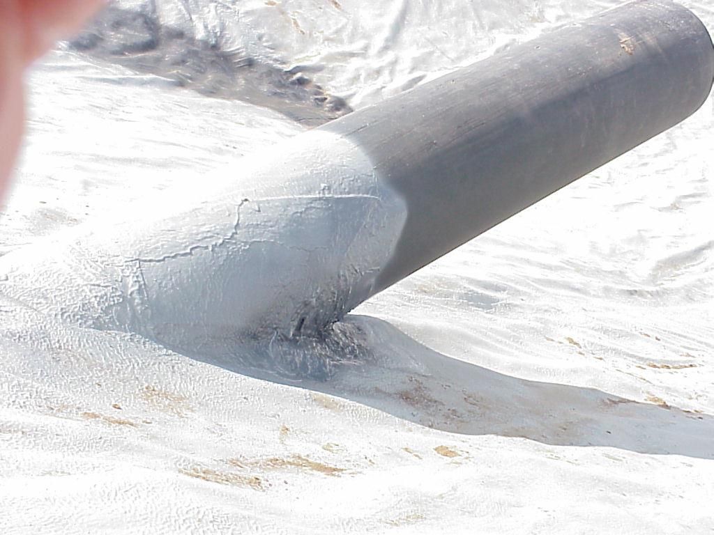 Close-up of a black pipe or hose on a bright white tarp or snow-covered surface.
