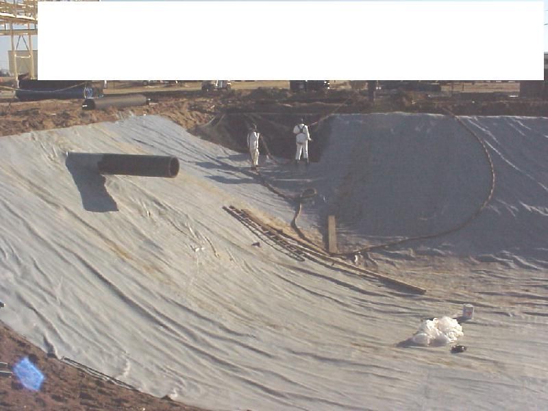 Large black liner in a wastewater pond with two workers standing near the top edge