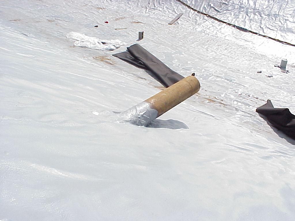 Cigarette butt on snowy ground beside torn black plastic debris.
