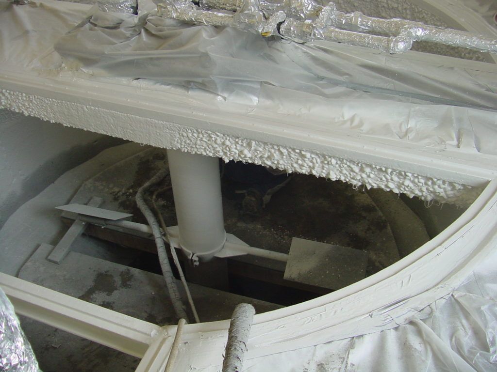 Curved white window frame showing a damaged roof opening with broken glass and debris inside