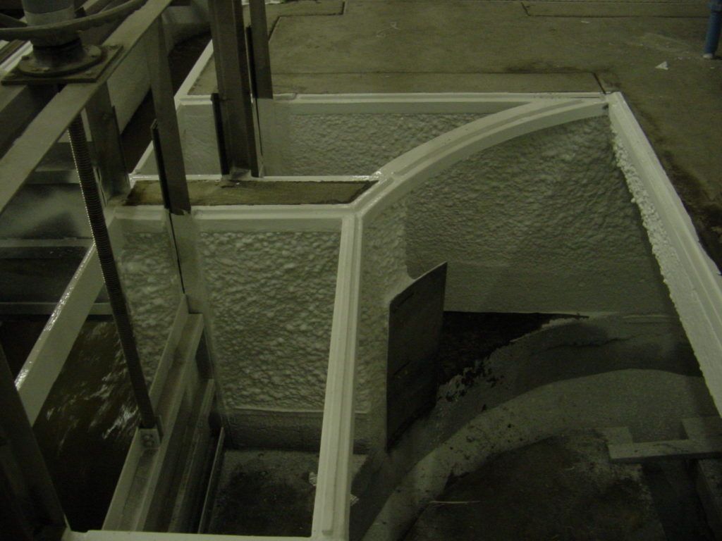Industrial staircase and metal railings beside a large circular tank or pit, viewed from above.