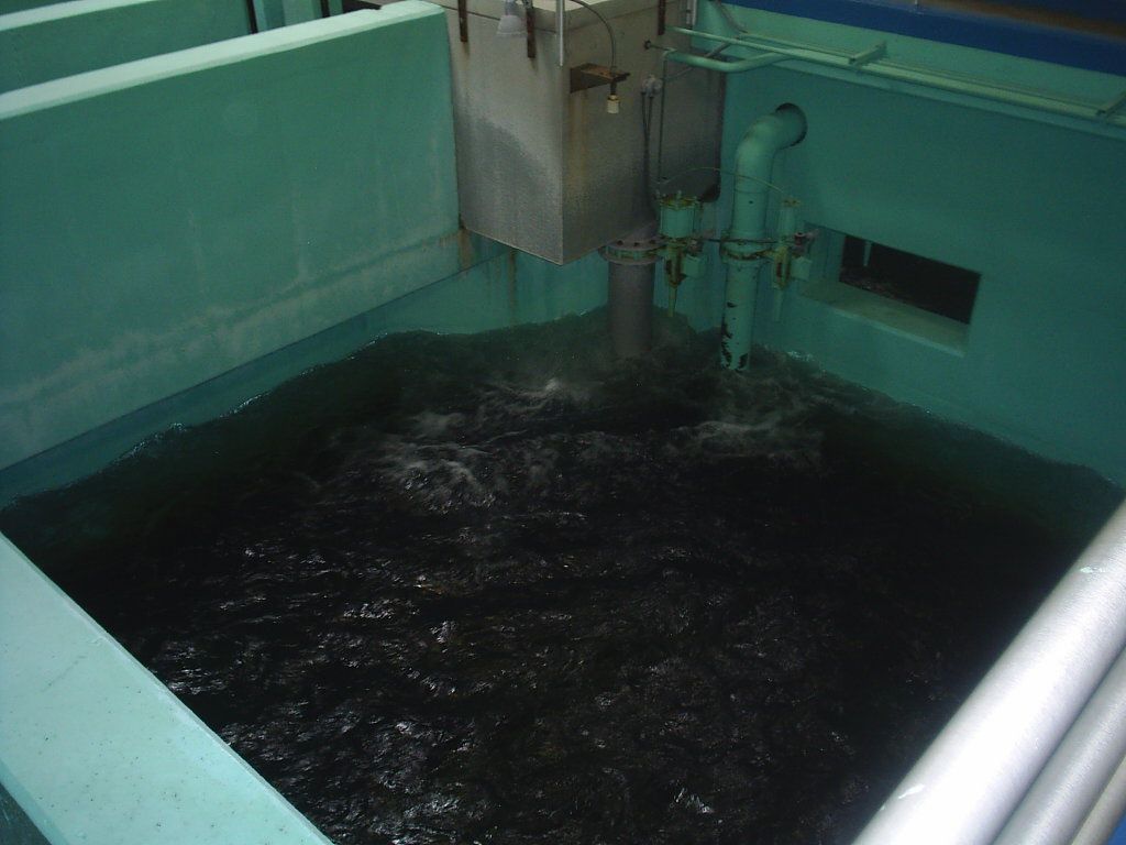 Dark liquid swirling in a teal industrial tank with a central metal mixer.