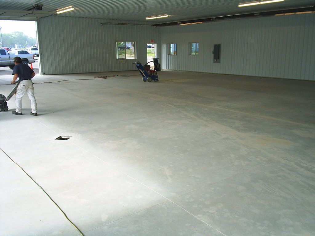 Large covered concrete space with two people at the far left and a stroller near the back wall.