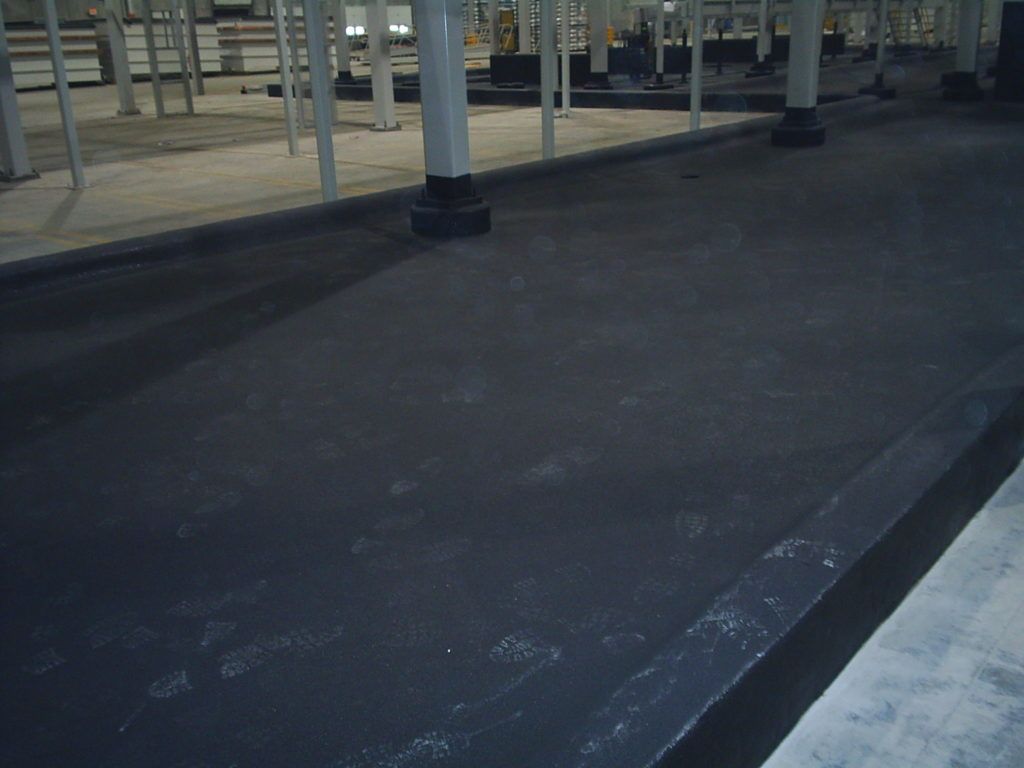Empty dark pavement under a covered structure with metal posts and railings.
