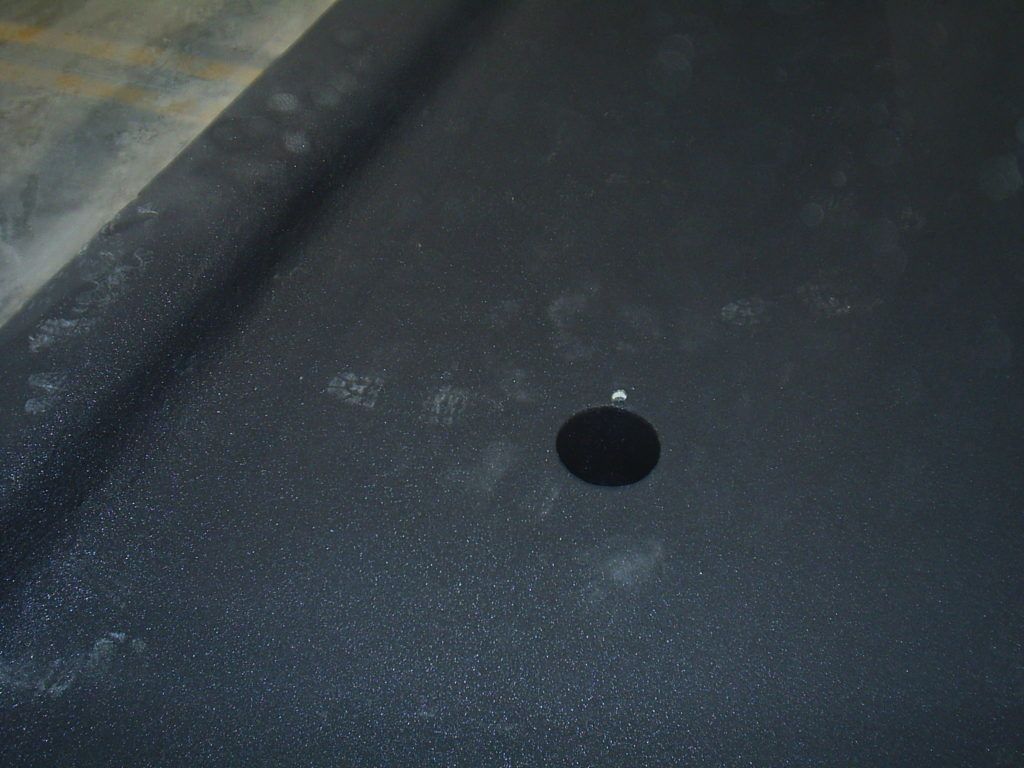 Close-up of a dark gray surface with a small black circular hole near the center.