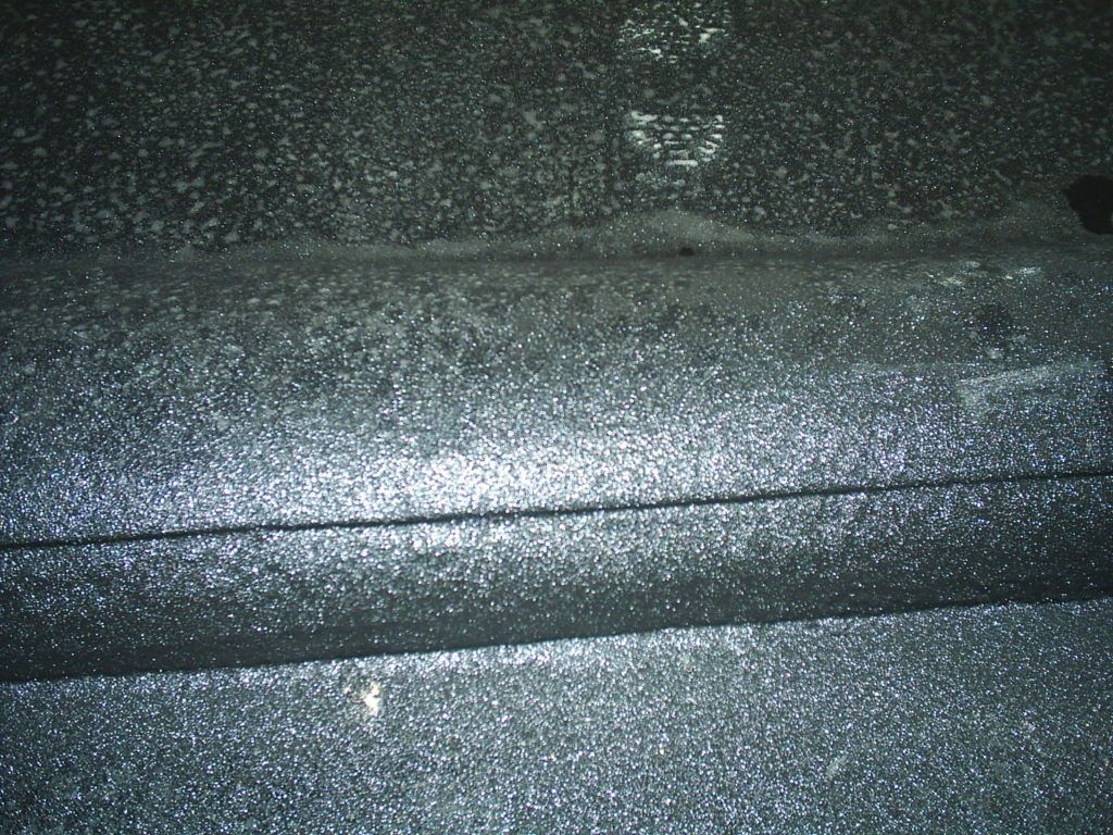 Close-up of a glittery dark fabric or surface with a diagonal seam and speckled reflections.
