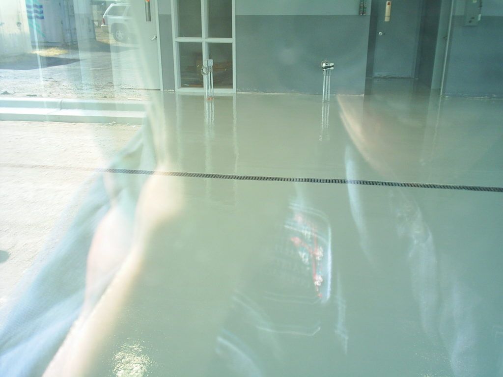 Reflection of a person in a car window, with a building and street visible outside
